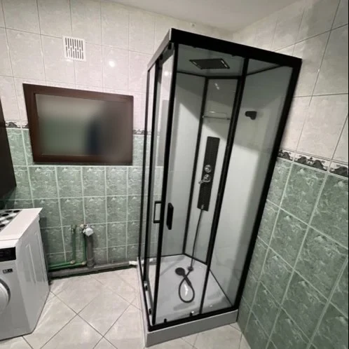 Łazienka z czarną kabiną prysznicową i pralką — DobryHydraulik Łódź